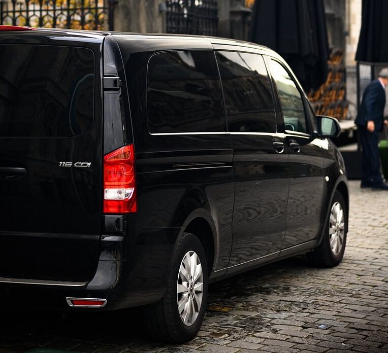 Minibus noir garé sur une rue pavée